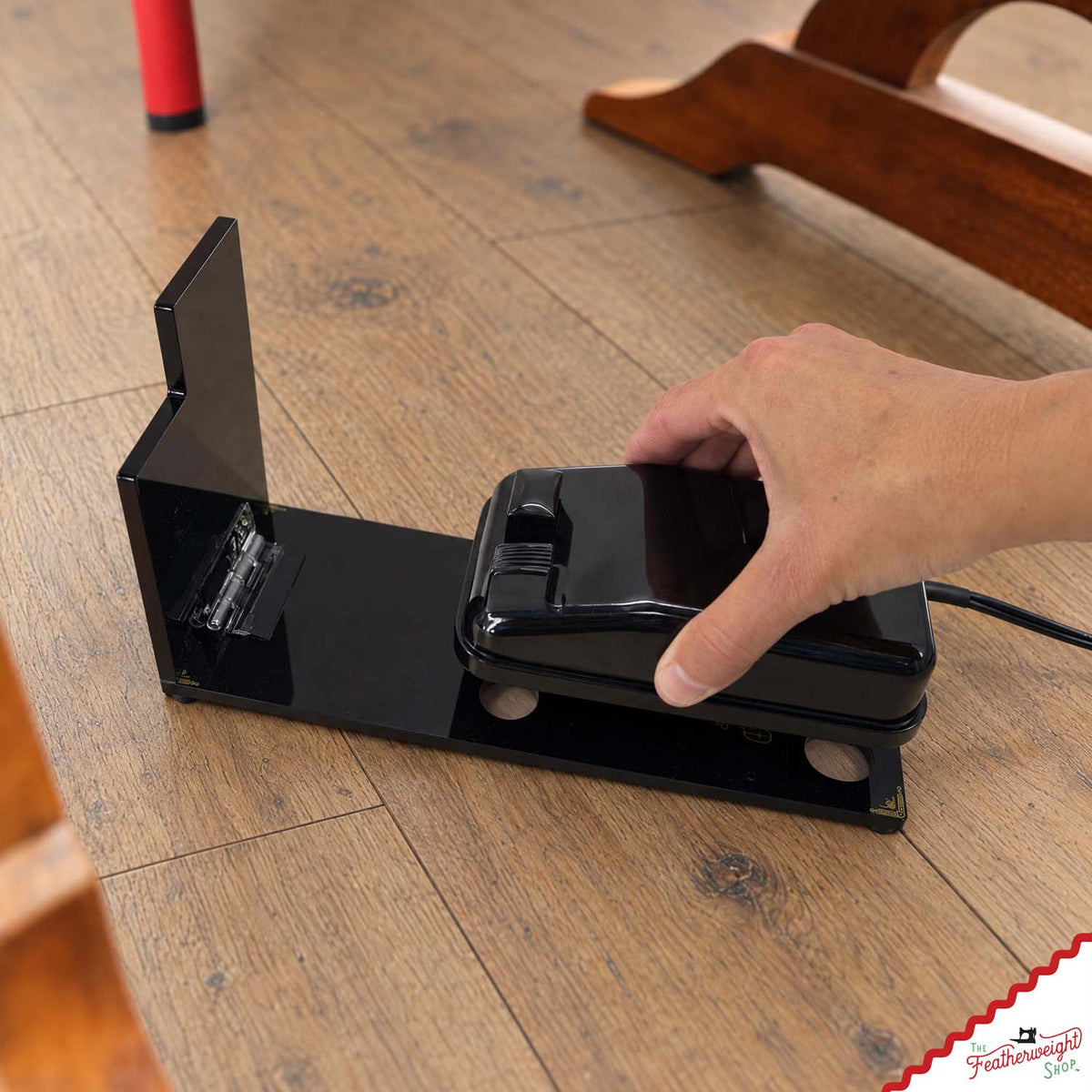 A hand setting the original foot pedal onto the adaptor’s base plate, the hinged paddle standing open