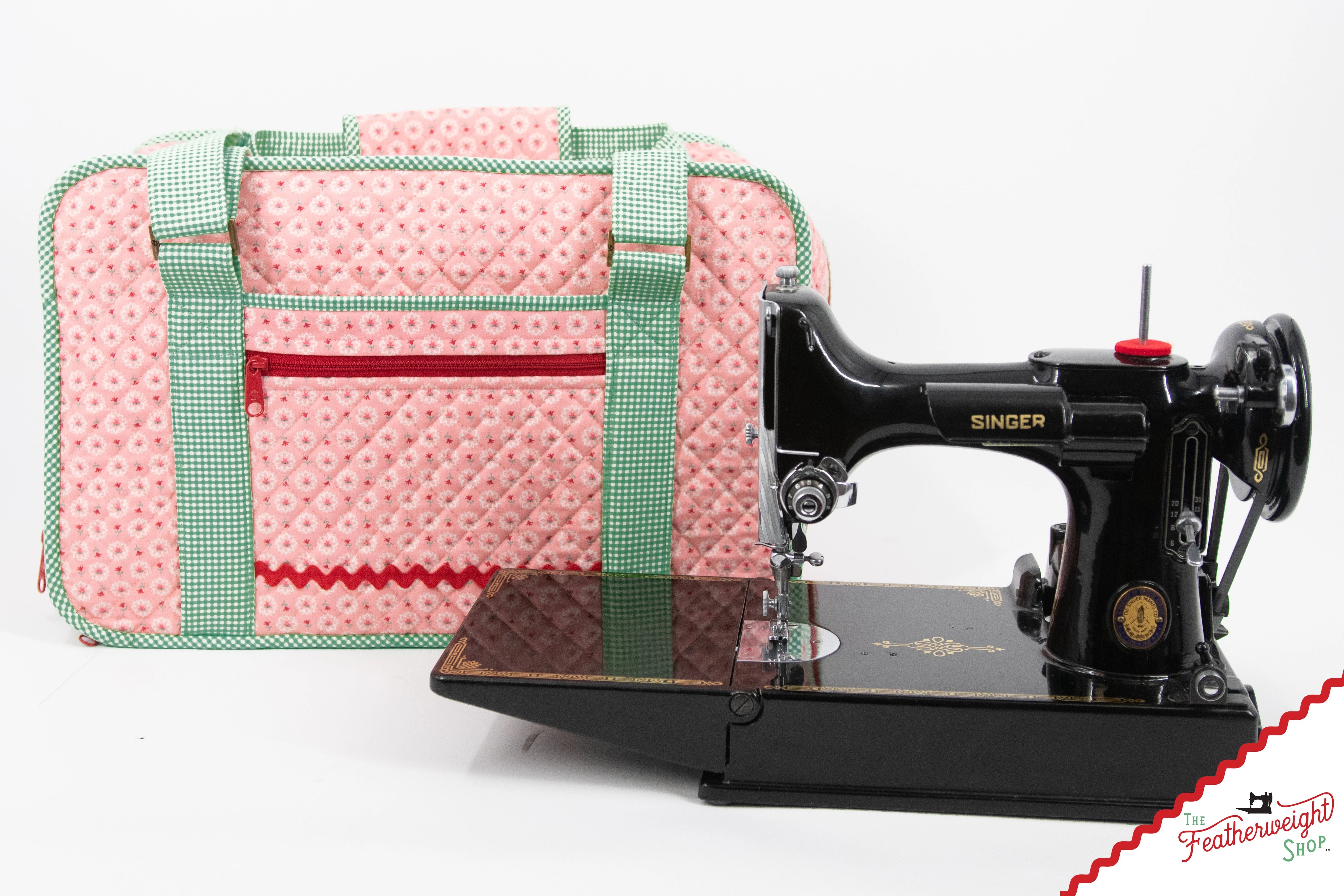 The Stitcher's Suitcase standing beside a black Singer Featherweight 221 sewing machine on a white background, showing that the bag is sized to carry the machine.