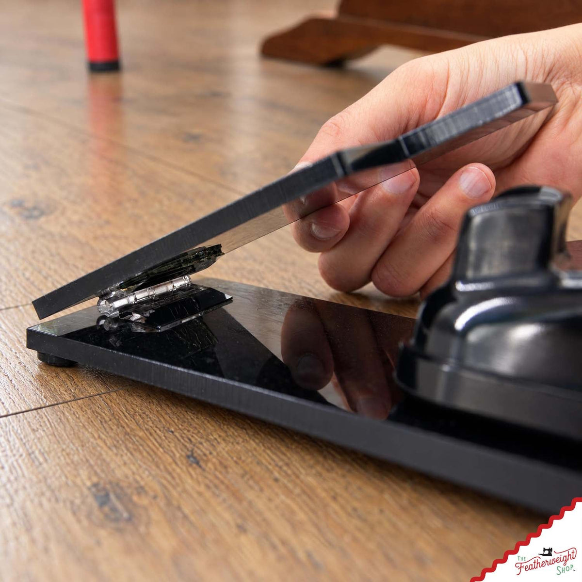 A hand lowering the adaptor’s hinged paddle over the original foot pedal