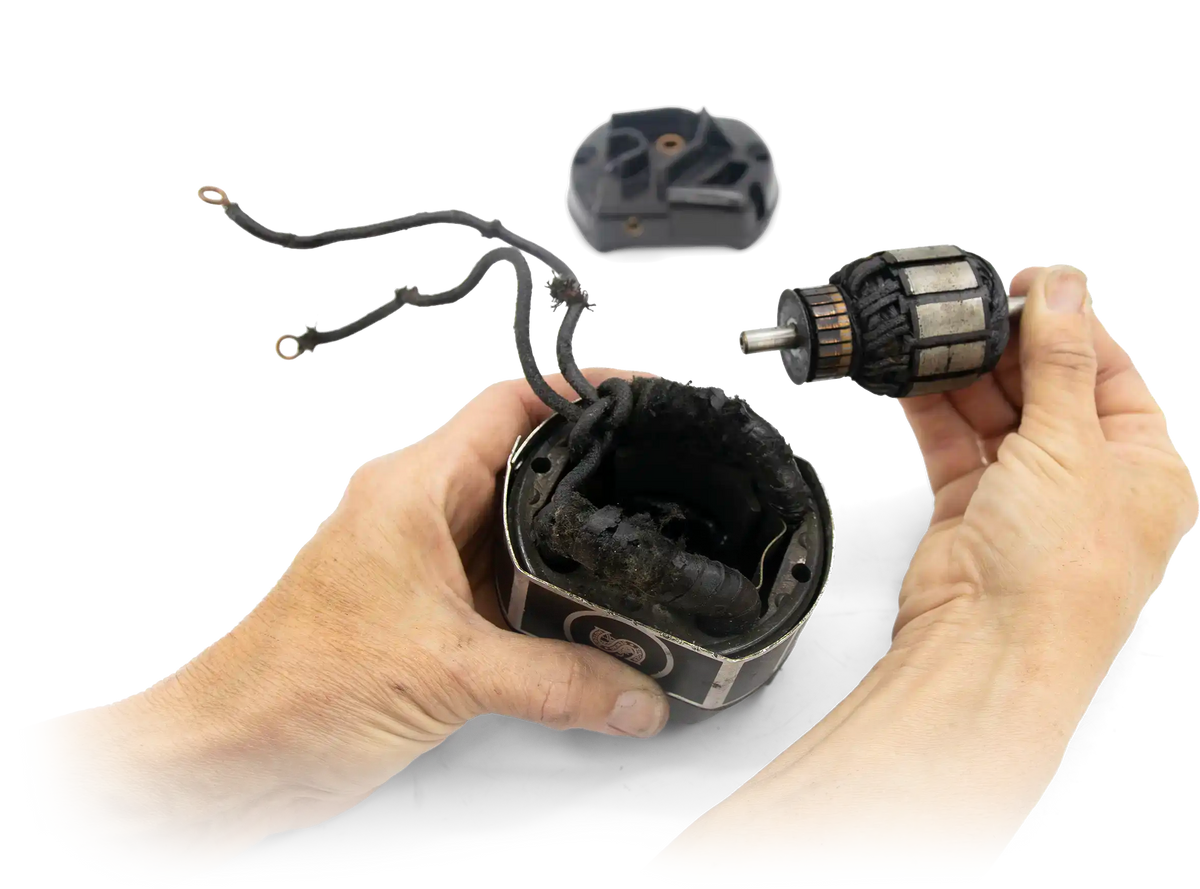 Hands lifting the worn original armature out of a Featherweight motor housing