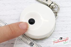 button for retracting tape measure