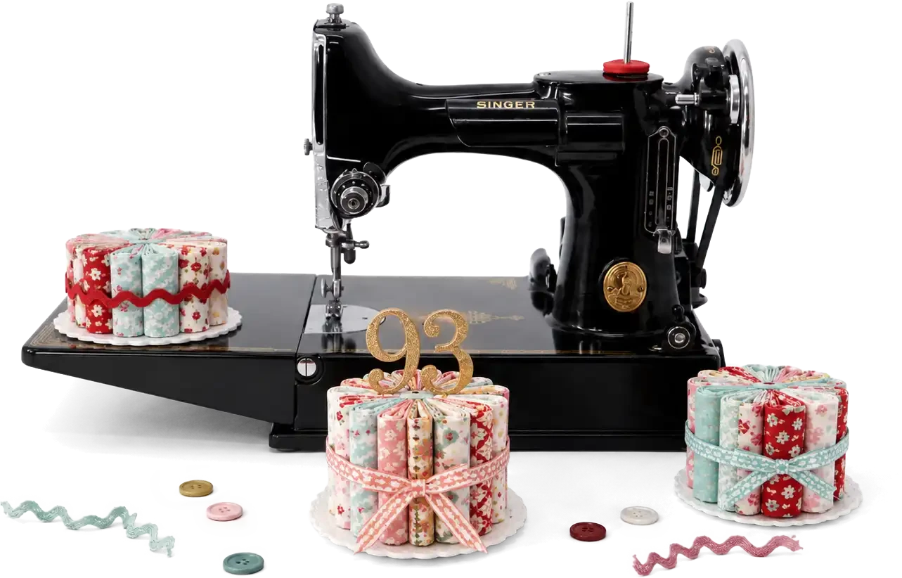 A black Singer Featherweight with three fabric-roll birthday cakes, one topped with a gold 93